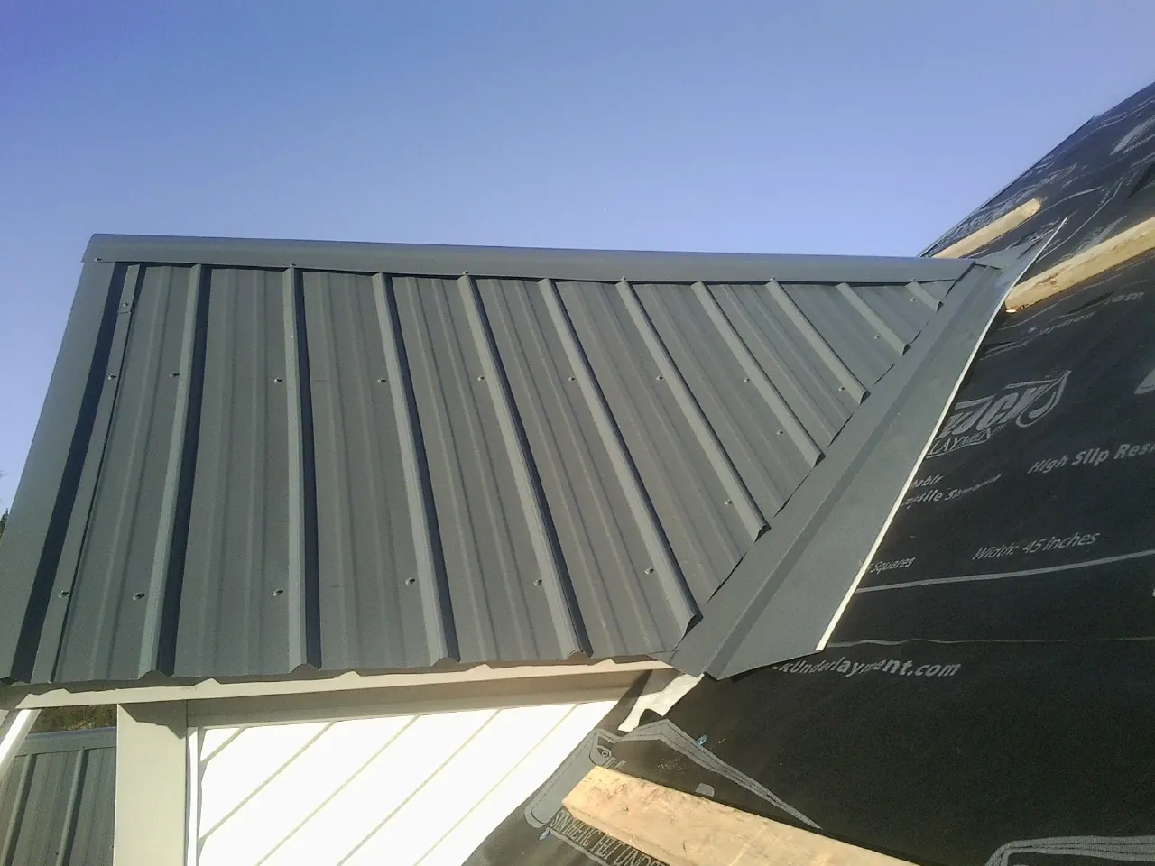 Gray metal roof panels going on over a garage gable in Peck