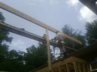 Carpenter setting a ridge beam over a new addition frame — Ice Dam Removal by Roofing Brothers in Peck